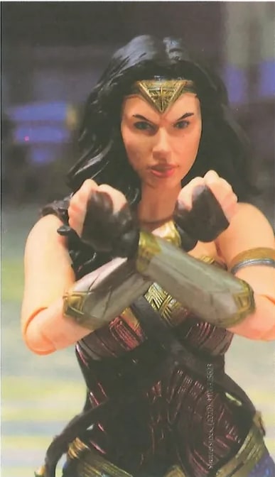 Imagen de la película 'La mujer maravilla' visible en el margen derecho de la página. Muestra a la protagonista (Gal Gadot) en postura de combate con su armadura dorada y escudo. Imagen de fotograma o afiche de la película.