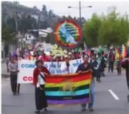 Marcha de la CONAIE con bandera multicolor por unidad y derechos.