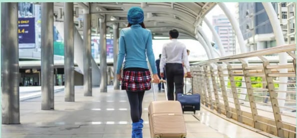 Fotografía de personas caminando en un aeropuerto/estación con maletas; alude a viajes vinculados a la actividad comercial.