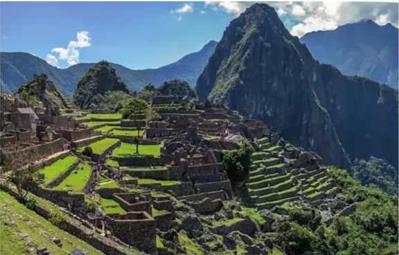 Fotografía clásica de Machu Picchu con la montaña Huayna Picchu al fondo y terrazas verdes.