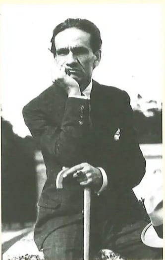 Fotografía en blanco y negro de César Vallejo, poeta peruano. Retrato del poeta en posición pensativa, con traje formal. Aparece a la derecha del texto biográfico. Crédito: Juan Domingo Córdoba (2020) www.commons.wikimedia.org.