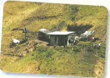 Fotografía de vivienda precaria en pendiente rural.