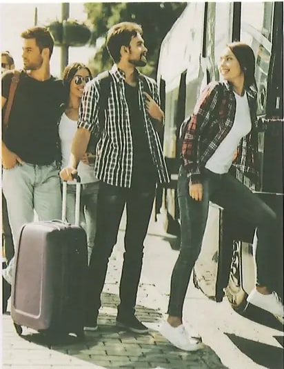 Fotografía de un grupo de jóvenes (hombre y dos mujeres) con maletas de viaje en una parada de transporte público, sonriendo. La imagen acompaña el texto 1 del ejercicio 1 sobre hermanos esperando el autobús. Crédito: Shutterstock (2020) 1217532163.