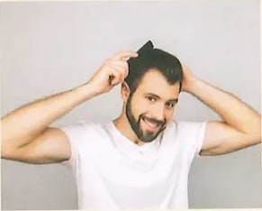 Fotografía de un hombre con camisa blanca que se mesa el cabello con ambas manos, con expresión graciosa. Ilustra el concepto de verbo reflexivo (a) con el ejemplo 'Yo me peino'. Crédito: Shutterstock (2020) 1192766260.