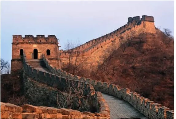 Fotografía de un tramo de la Gran Muralla China con torre de vigilancia y montañas.