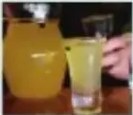 Vaso de chicha amarillenta junto a mazorca de maíz.